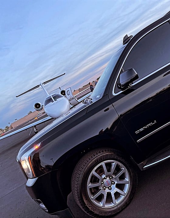 Black luxury SUV parked beside a private jet on the ramp at Scottsdale Airport