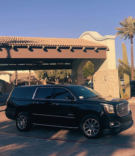 Black luxury SUV waiting under a Spanish-tile porte-cochere with a saguaro and palm at a Scottsdale resort