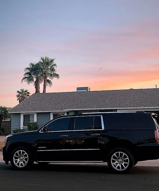 Side profile of a black GMC Yukon XL Denali at sunset with palm trees, Phoenix